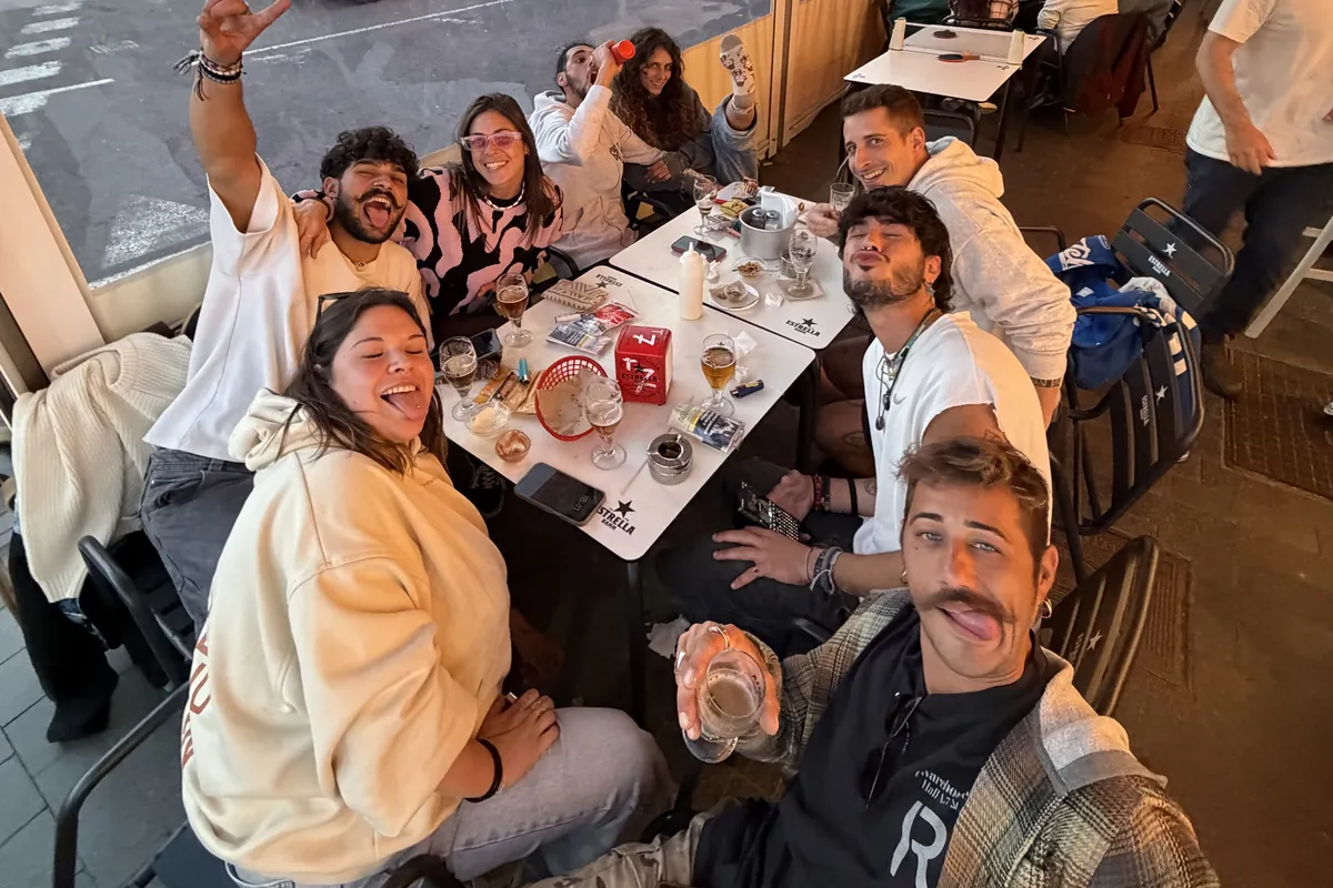 Un grupo de amigos alrededor de una mesa en la terraza, sonriendo a la c&aacute;mara con la luz del atardecer