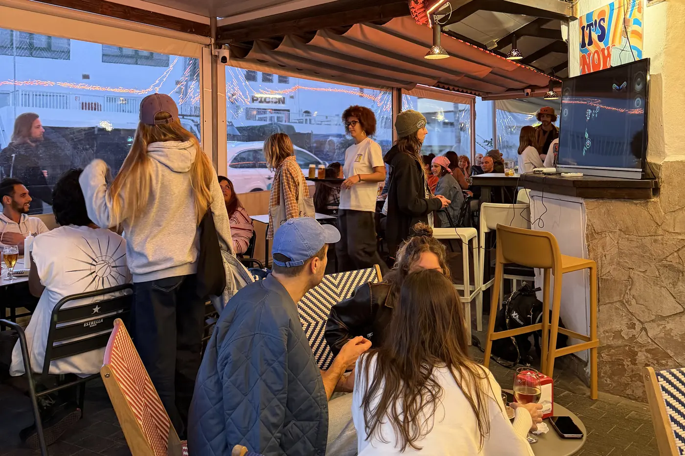 La terraza cubierta llena de gente al atardecer, con el equipo trabajando en la barra al fondo